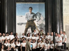 A choir poses before an image of Pier Giorgio Frassati during a celebration of the centenary of his death, Turin, Italy, Friday, July 4, 2025.