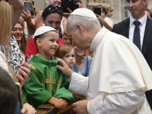 Pope Leo XIV greets a young papal admirer in St. Peter’s Basilica during the general audience on Wednesday, Aug. 20, 2025, at the Vatican.