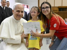 Pope Leo XIV receives a drawing from a girl participating in the “Estate Ragazzi in Vatican” summer camp on July 3, 2025, at the Vatican.