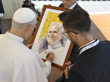 Pope Leo XIV signs a portrait of himself for a pilgrim at his general audience on July 30, 2025, in St. Peter’s Square at the Vatican.